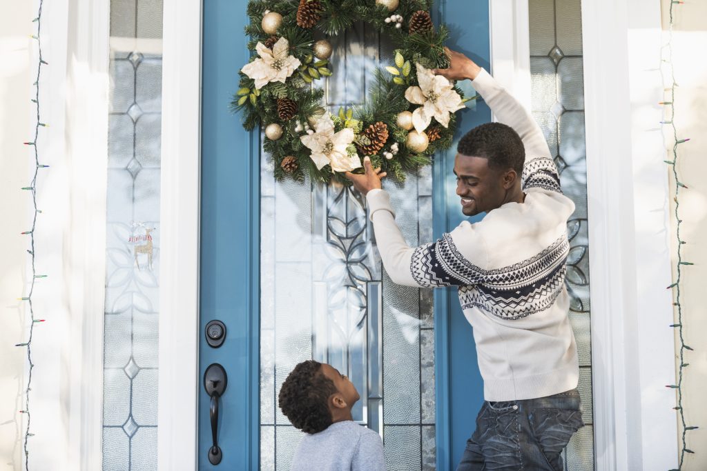 African American father and son hanging wreath on front door