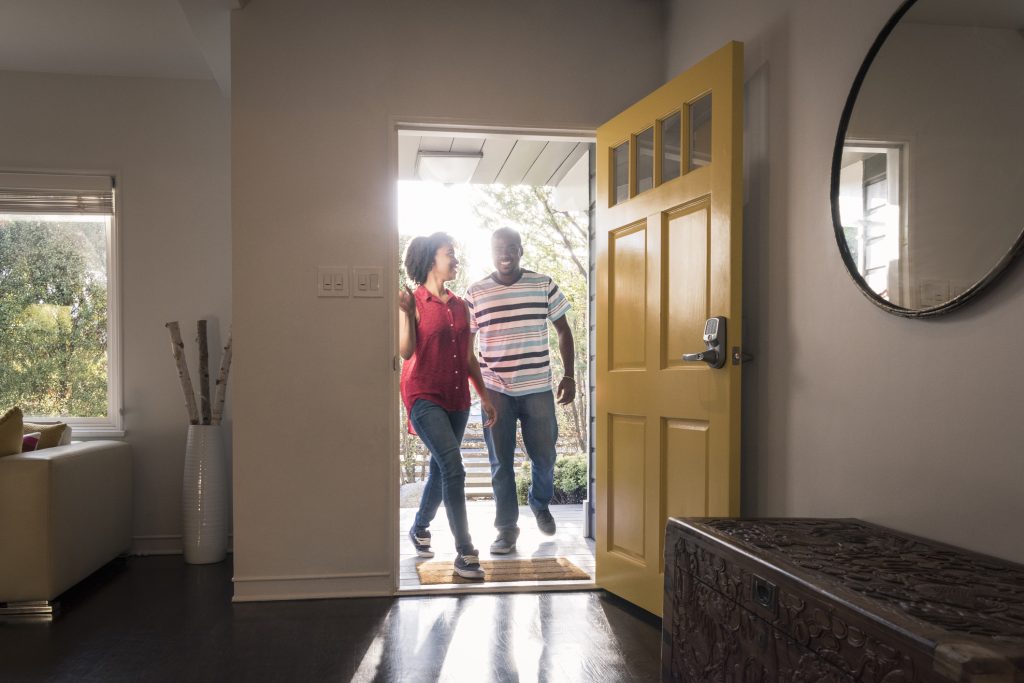 African American couple arriving home in doorway, smiling